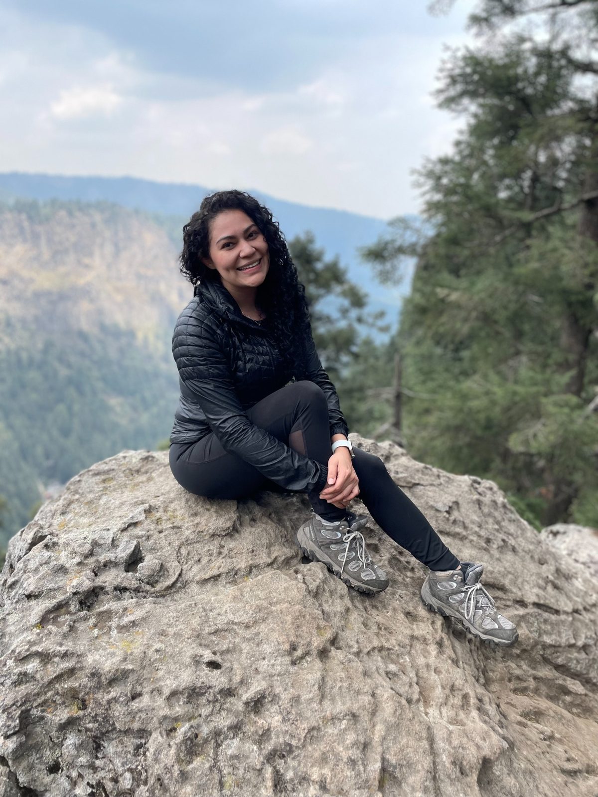 Corina sitting on a rock in the mountains